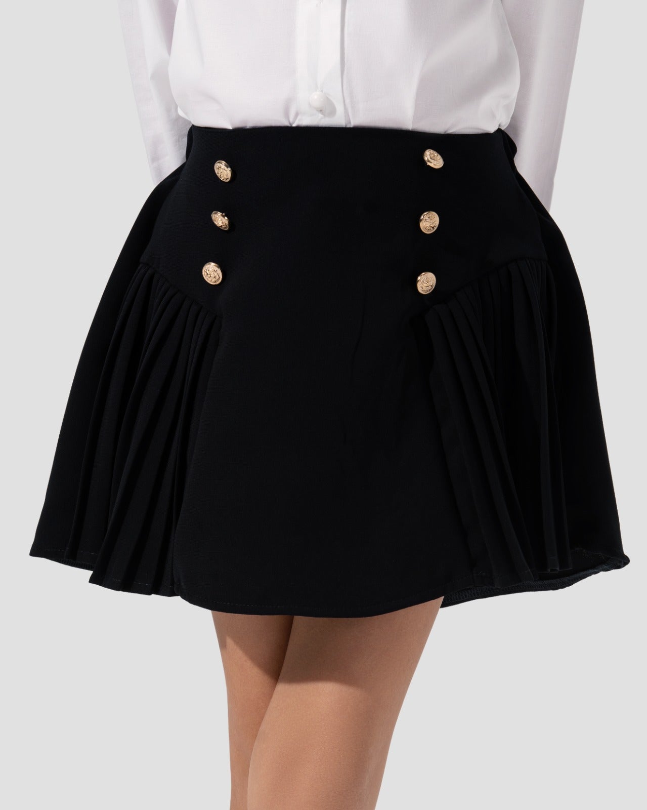 Short pleated skirt in navy blue with gold-tone button detail at the waist