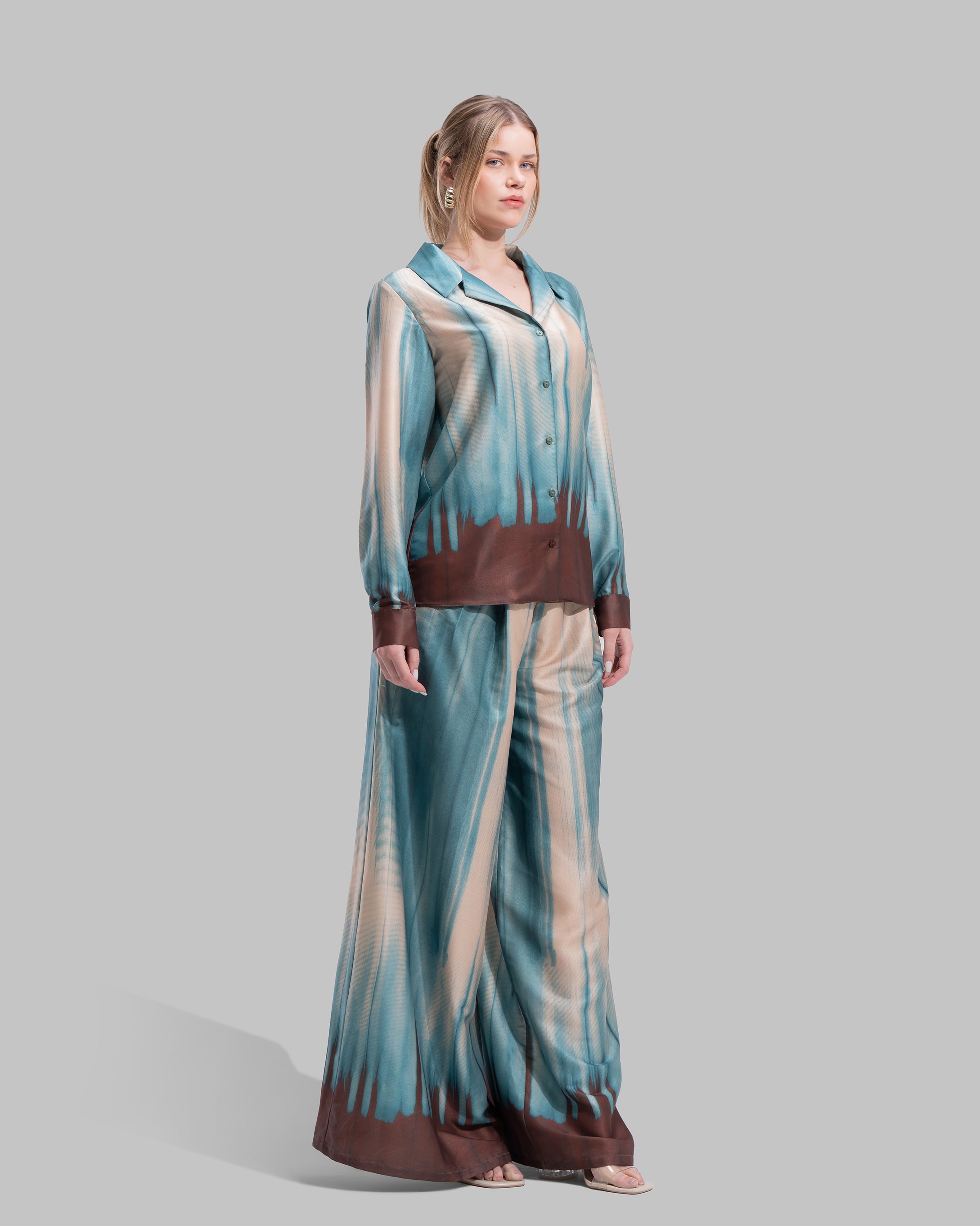 A long-sleeved button-down shirt featuring a teal and cream gradient print with a dark brown hem.