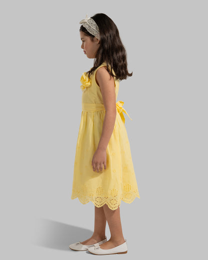 sleeveless pink cotton eyelet dress featuring a floral appliqué on the chest and a matching waist belt.